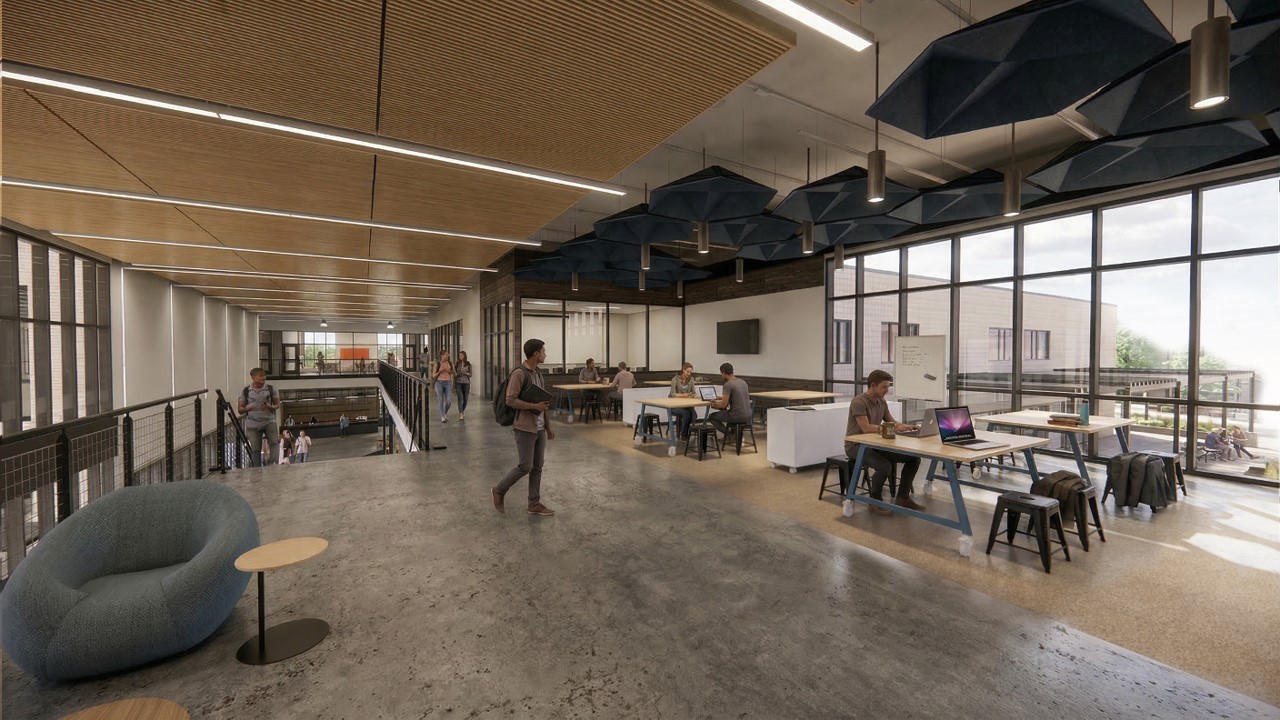 Modern open workspace with people working at tables, walking, and talking. There are large windows, concrete floors, a lounge chair, and blue ceiling panels, creating a bright, collaborative environment.